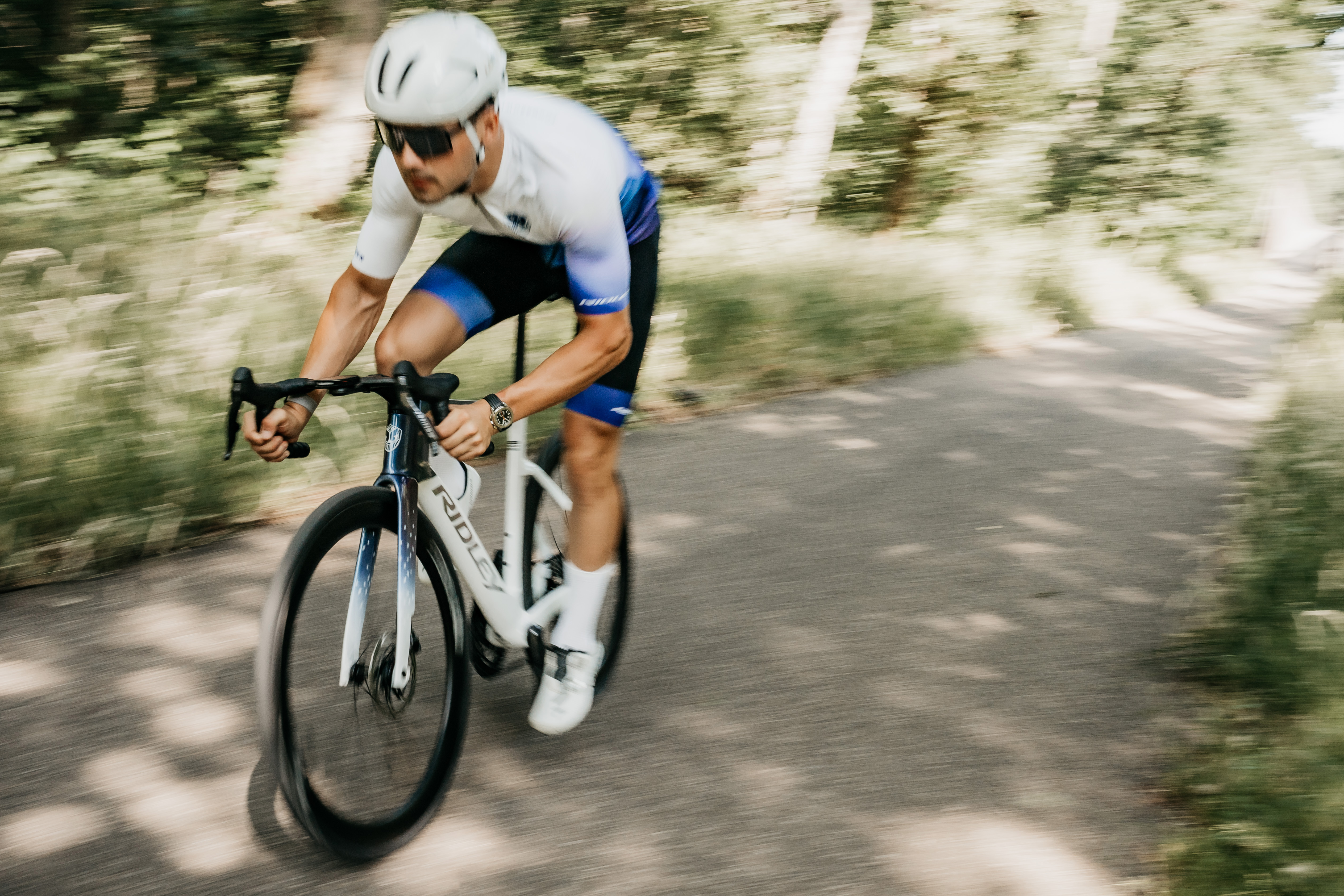 Side profile of an aero-optimized race bike on flat terrain highlighting deep-section tubes and integrated cockpit