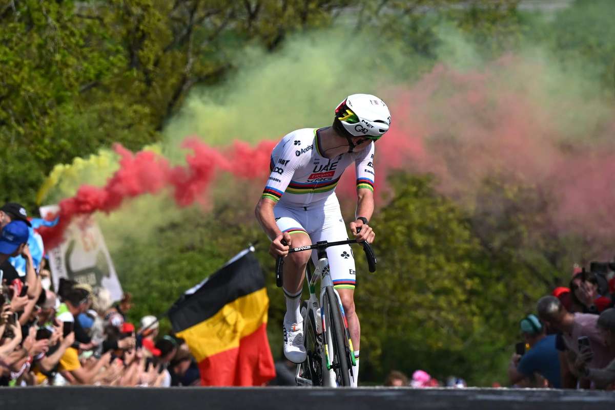 Riders powering over a long cobblestone sector with mud splatter and tense expressions