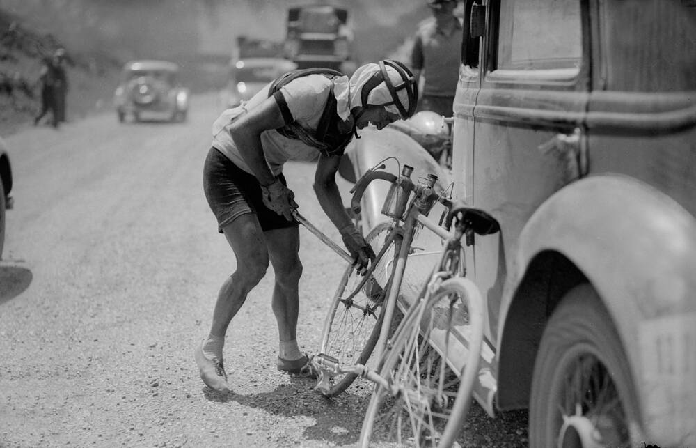 Jean Robic climbing a steep switchback during mountain training, pedals blurred with effort