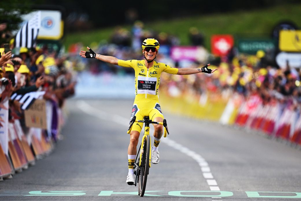 Tour de France winner raising trophy on podium with team celebrating