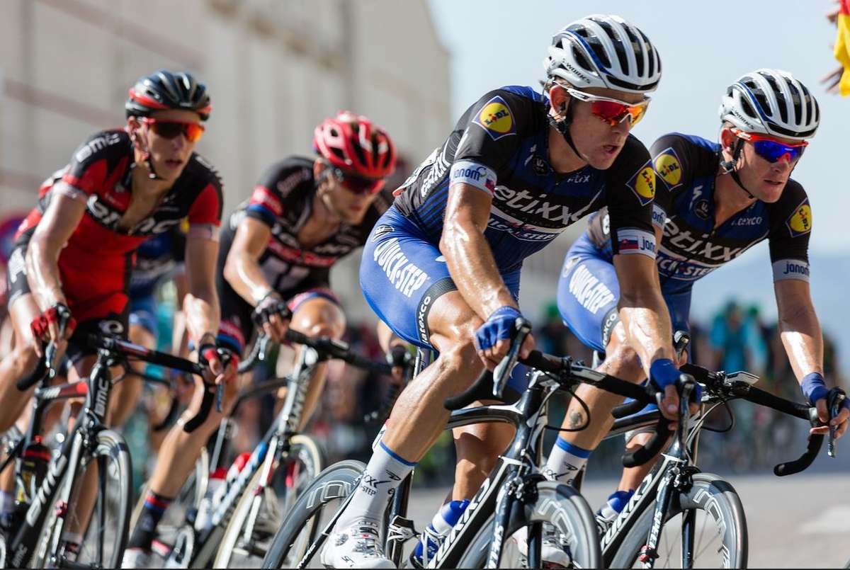 Race time trialist in an aerodynamic tuck on a flat open road under clear skies