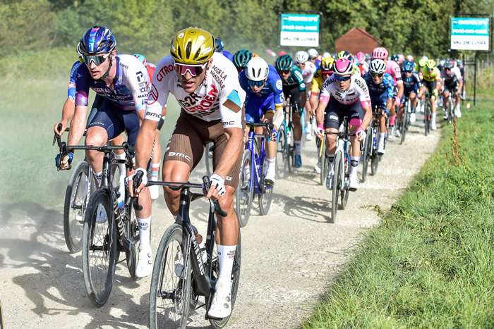 Small breakaway group forming gap after cresting a summit with chase group in the distance
